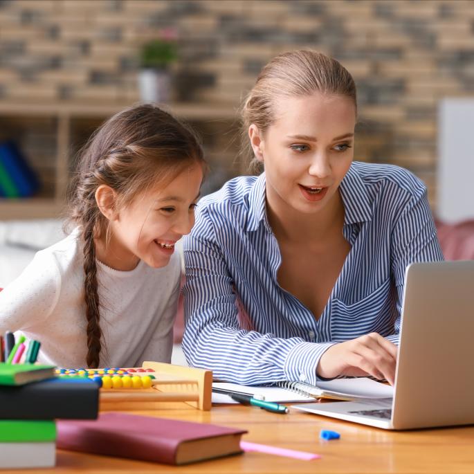 Adult and child looking at a laptop and smiling.