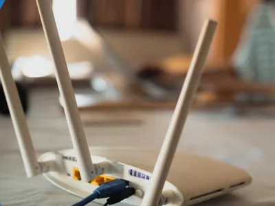 A white wifi router with antennae and cables plugged into it