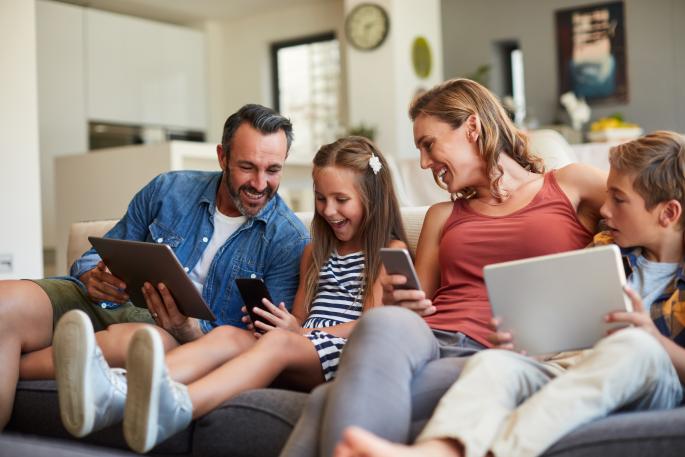 Family playing with devices on the sofa