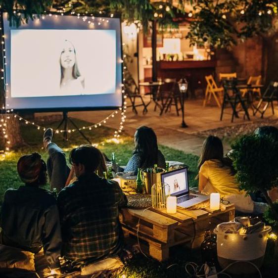 People watching movie on projector screen outdoors