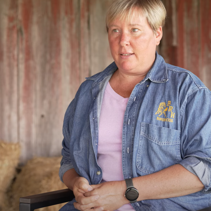 Woman sitting in wooden barn with hay bales