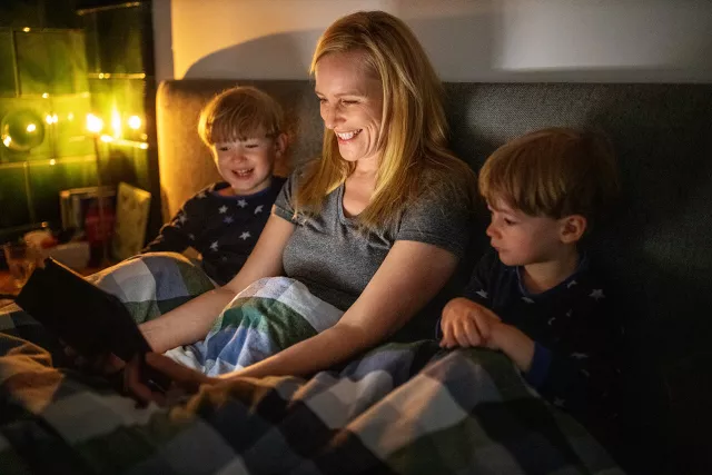 Photo of mother and children watching a tablet together on a sofa