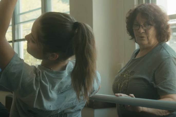 Photo from video capturing a ballerina in pose and her teacher looking on